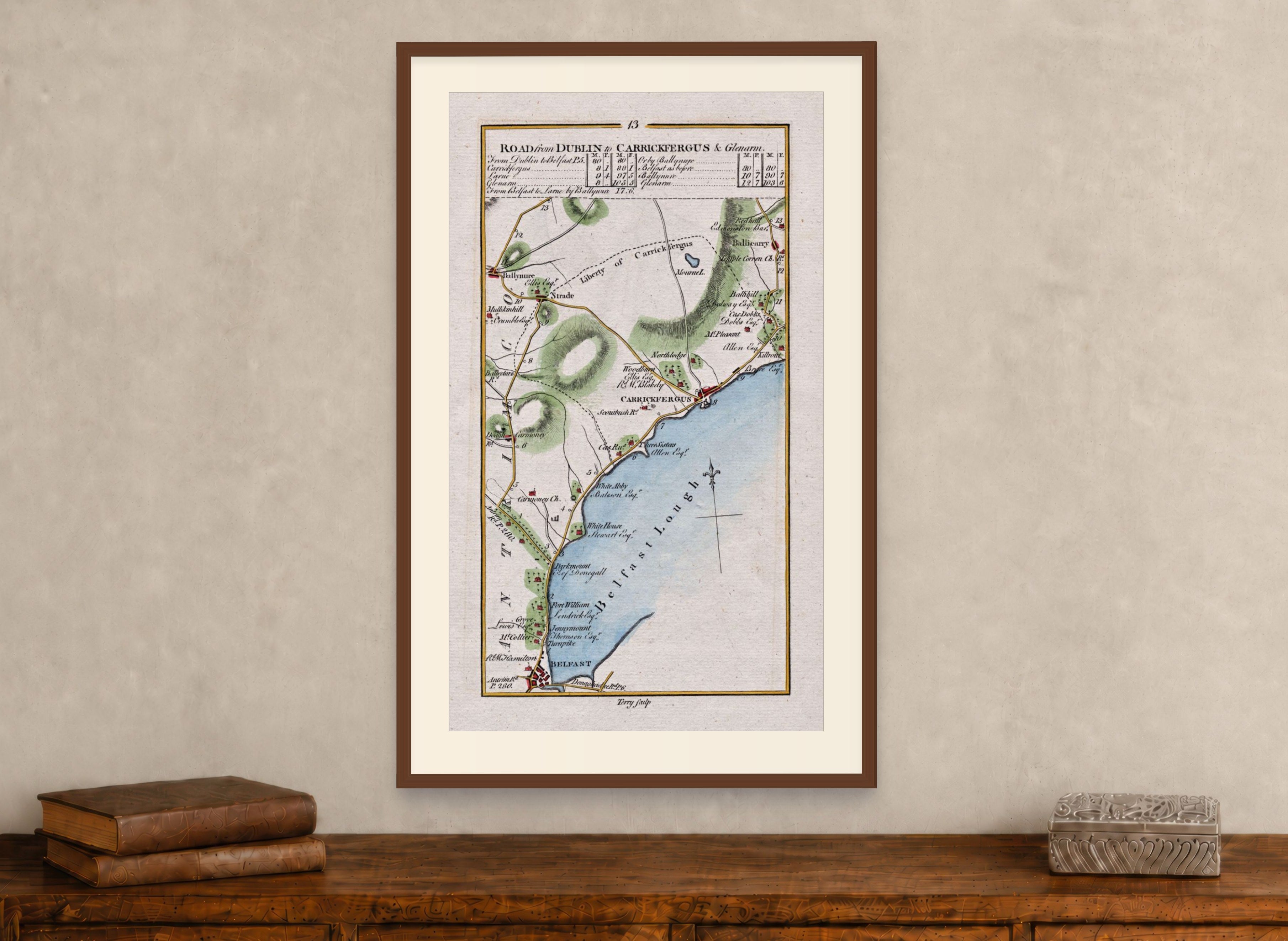 Framed 1783 Taylor & Skinner Belfast, Carrickfergus, Ballynure, Whiteabbey and Ballycarry, Ireland road map displayed above an antique wooden cabinet.