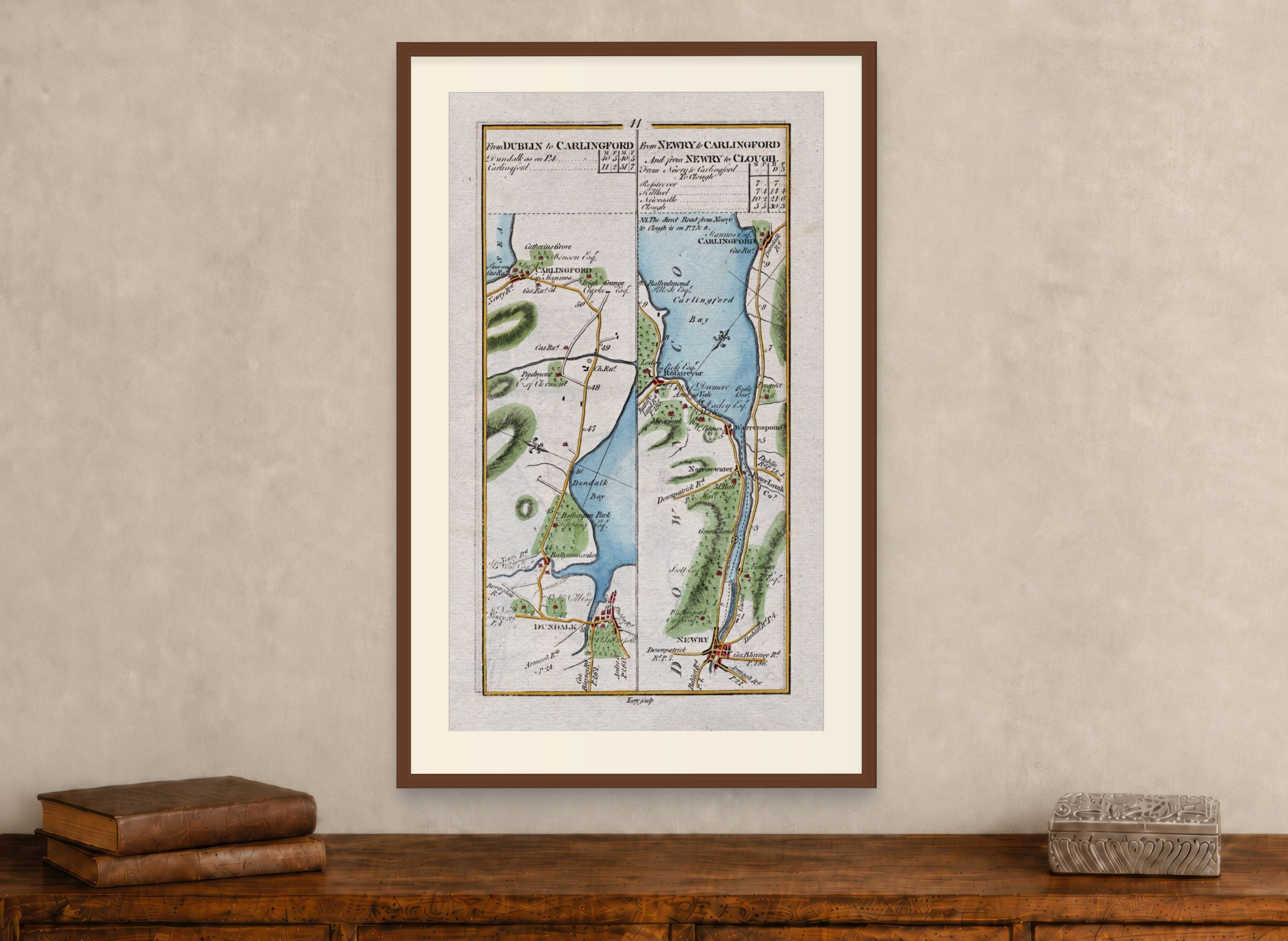 Framed 1783 Taylor & Skinner Ireland road map showing Dundalk, Carlingford, Newry, Warrenpoint and Rostrevor, displayed above an antique wooden cabinet.
