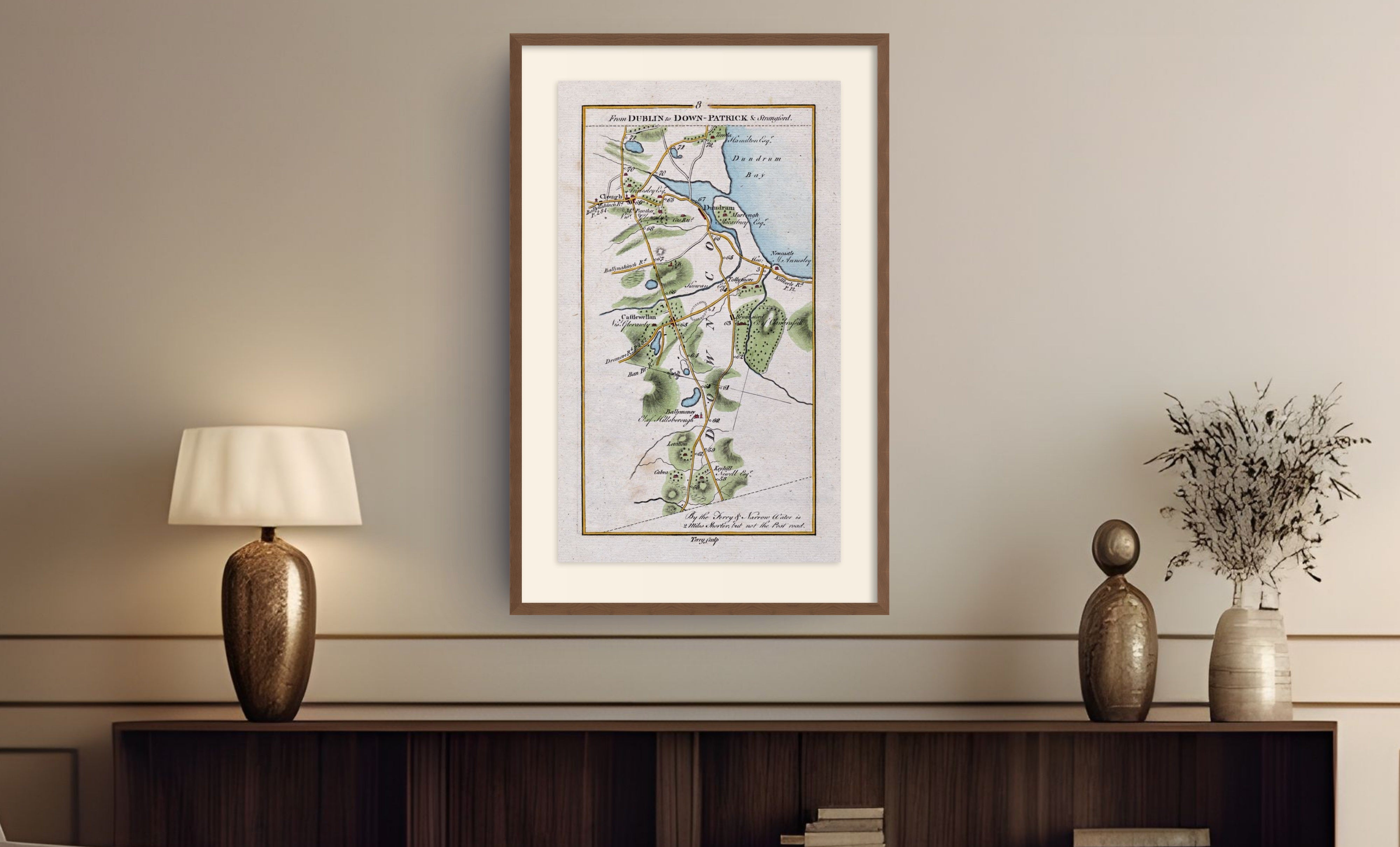 Framed antique Ireland road map of Newcastle, Castlewellan, Dundrum and Clough displayed in a styled room interior.