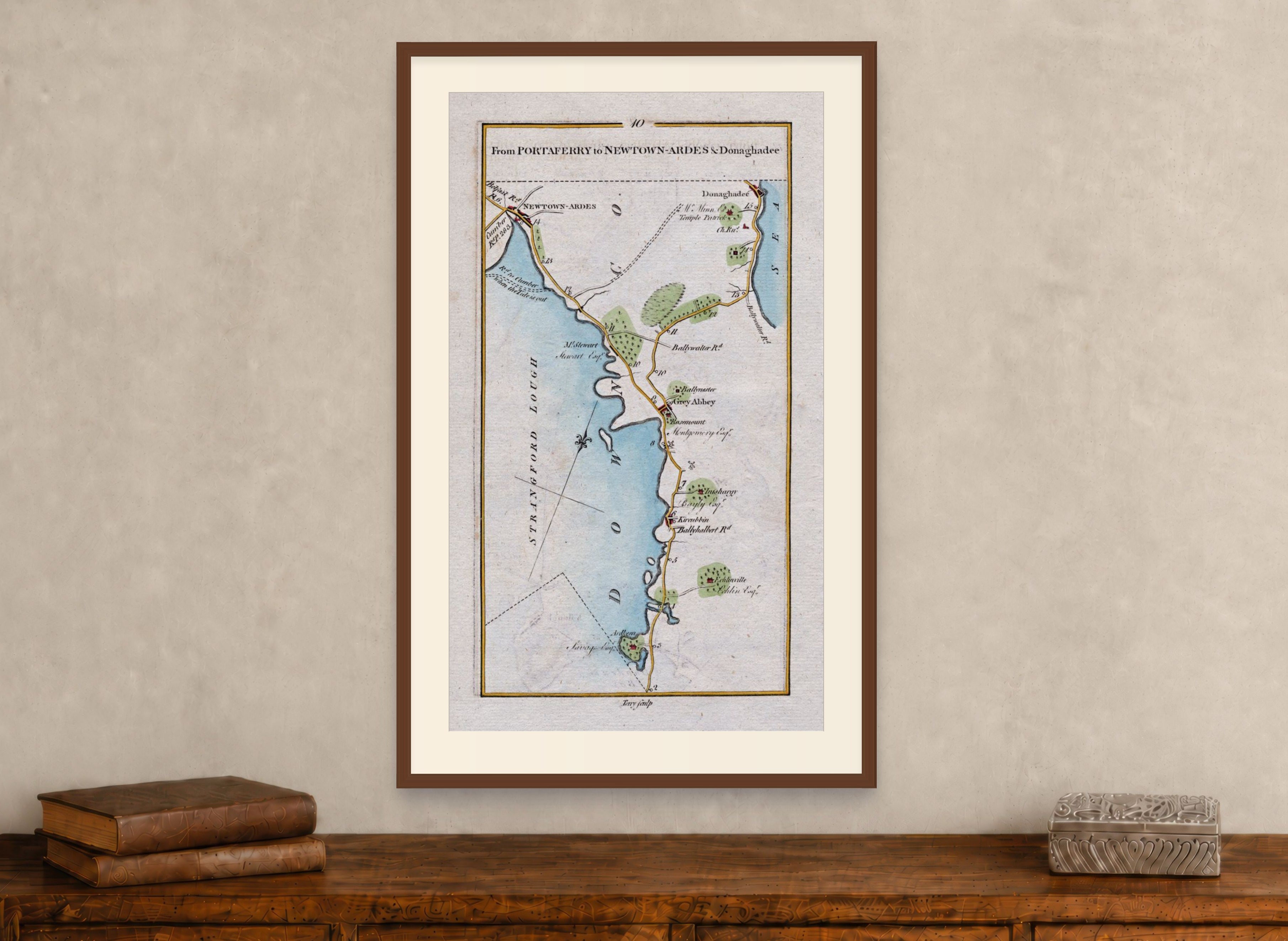 Framed 1783 Taylor & Skinner Ireland road map showing Newtownards, Donaghadee, Greyabbey and Kircubbin, displayed above an antique wooden cabinet.