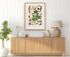 1879 Zomicarpa pythonium antique botanical print, Plate 2 by Heinrich Wilhelm Schott, framed above a natural oak sideboard in a bright, neutral living room.
