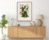 1879 Anthurium bellum antique botanical print, Plate 11 by Heinrich Wilhelm Schott, framed above a natural oak sideboard in a bright, neutral living room.