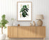 1879 Philodendron imbe antique botanical print, Plate 34 by Heinrich Wilhelm Schott, framed above a natural oak sideboard in a bright, neutral living room.