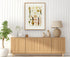 1879 Philodendron longilaminatum antique botanical print, Plate 36 by Heinrich Wilhelm Schott, framed above a natural oak sideboard in a bright, neutral living room.