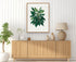 1879 Philodendron cannaefolium antique botanical print, Plate 38 by Heinrich Wilhelm Schott, framed above a natural oak sideboard in a bright, neutral living room.